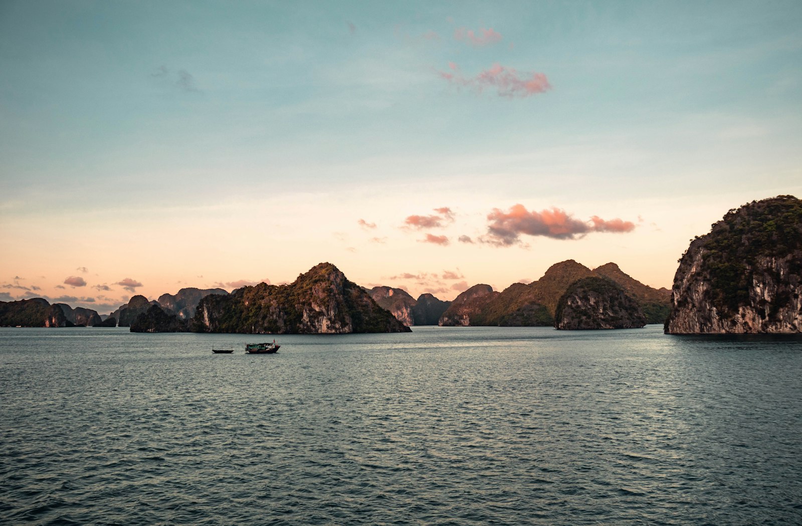 Limestone islands of Ha Long Bay under a pastel evening sky
