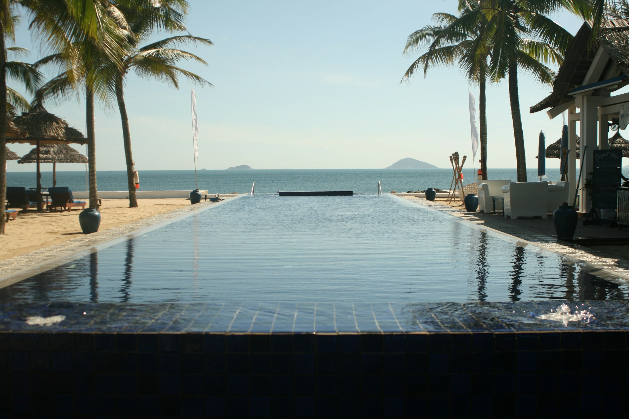 Infinity pool between coconut palms, opening onto the sea off the coast of Vietnam
